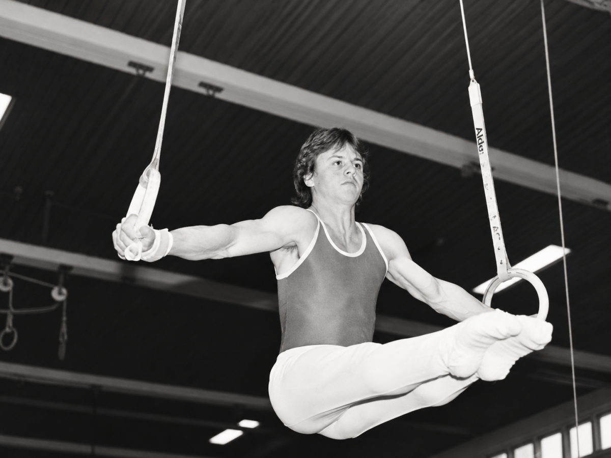 Yves Depallens en 1989, réalisant une figure de force aux anneaux lors d'un exercice de gymnastique artistique.