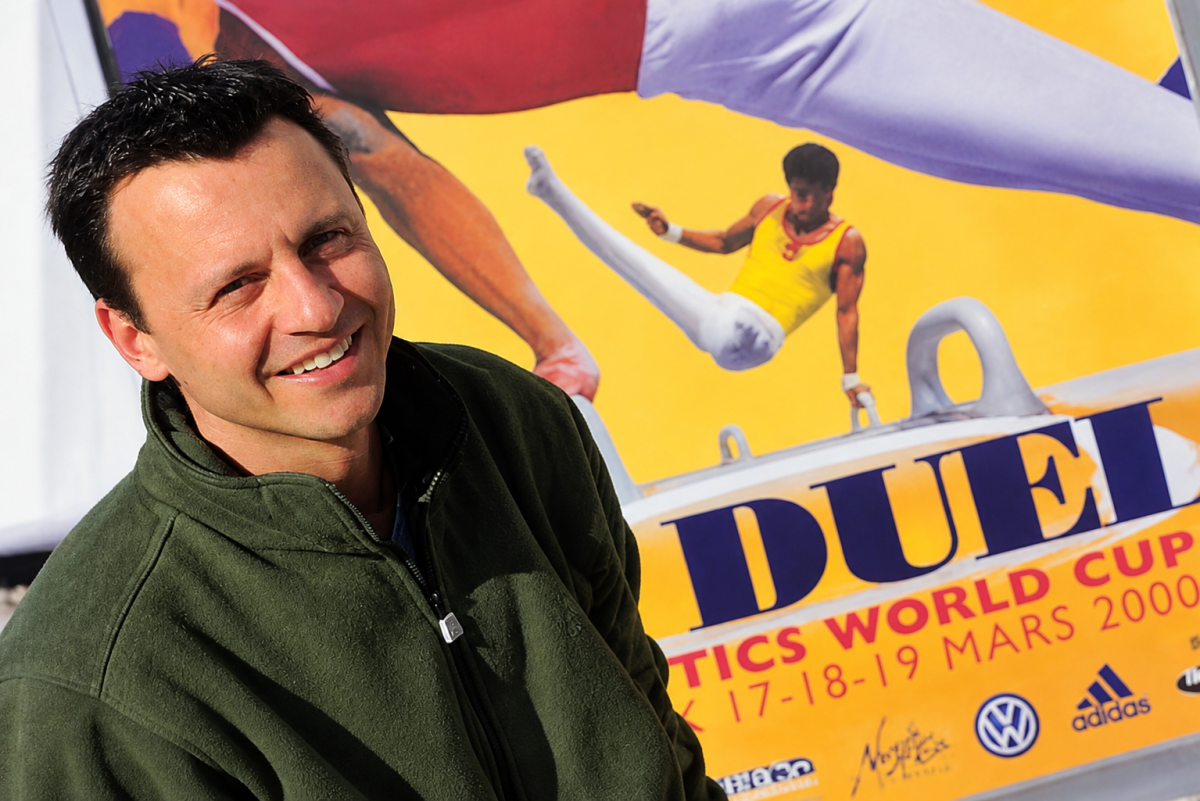 Yves Depallens devant l'affiche du Duel, Coupe du monde de gymnastique artistique organisée à Montreux en 2000