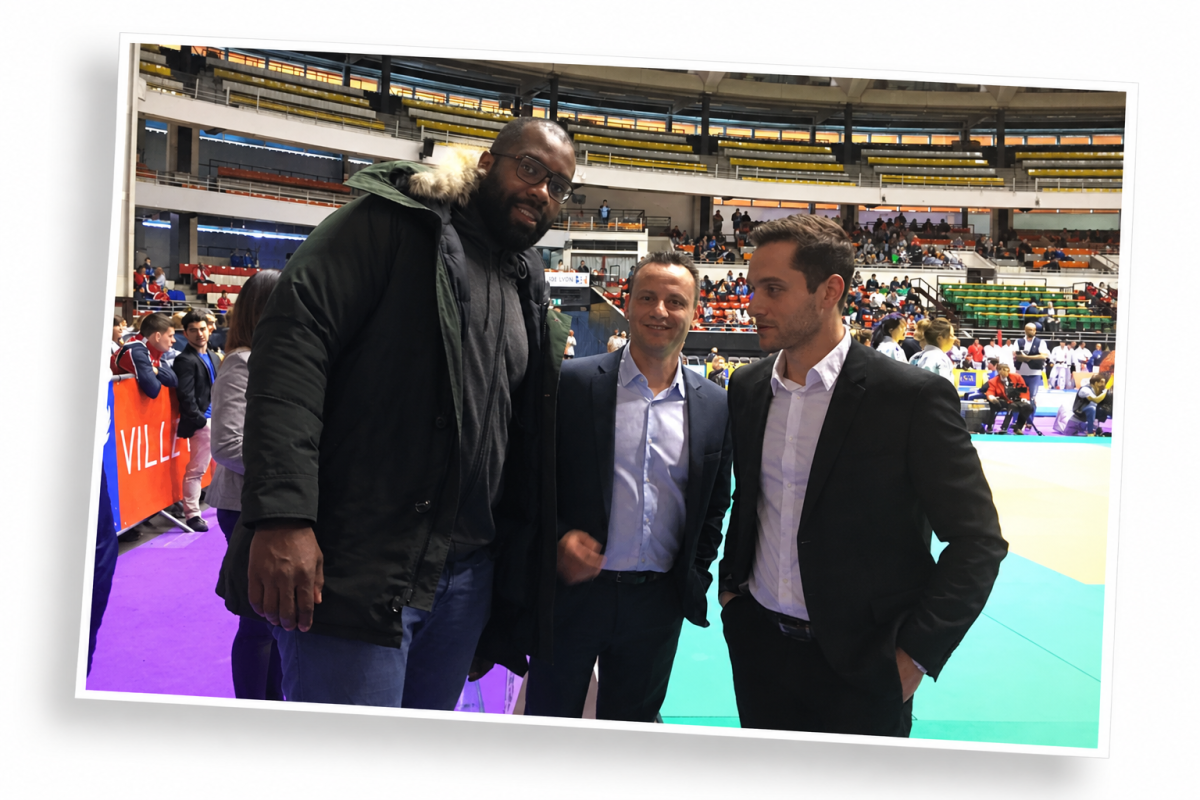 Yves Depallens alongside judoka Teddy Riner and a third participant at a sports venue hosting an international competition.